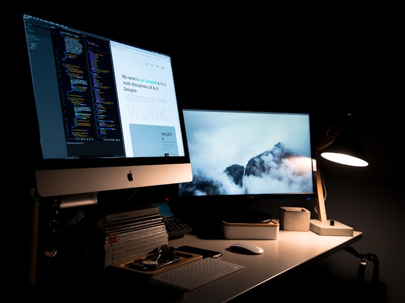 Designer travaillant avec deux écrans — code et site web en parallèle