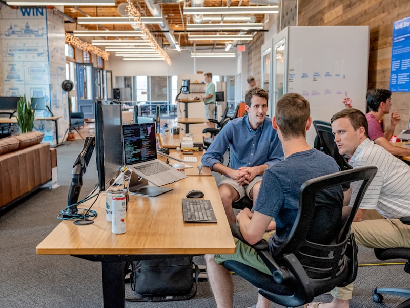 Deux développeurs en discussion à un bureau dans un open-space lumineux