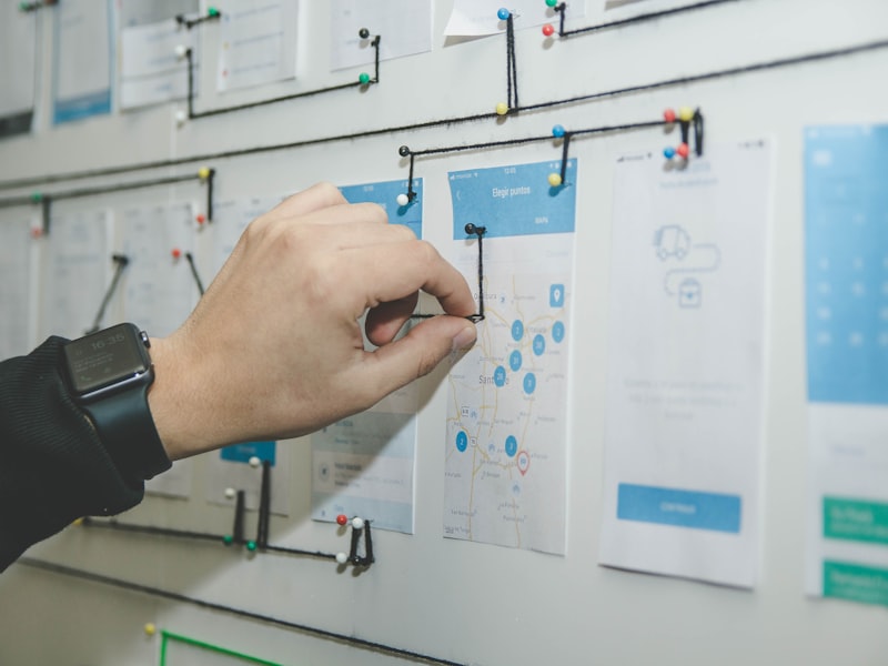 Planche de wireframes mobiles épinglée et reliée par fils — étape de stratégie UX