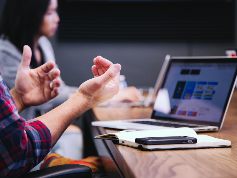 Stratège expliquant un design à un client lors d'une rencontre — main qui gesticule devant un portable