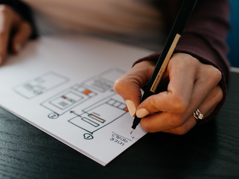 Designer dessinant un wireframe d'application mobile au crayon — refonte UX en cours